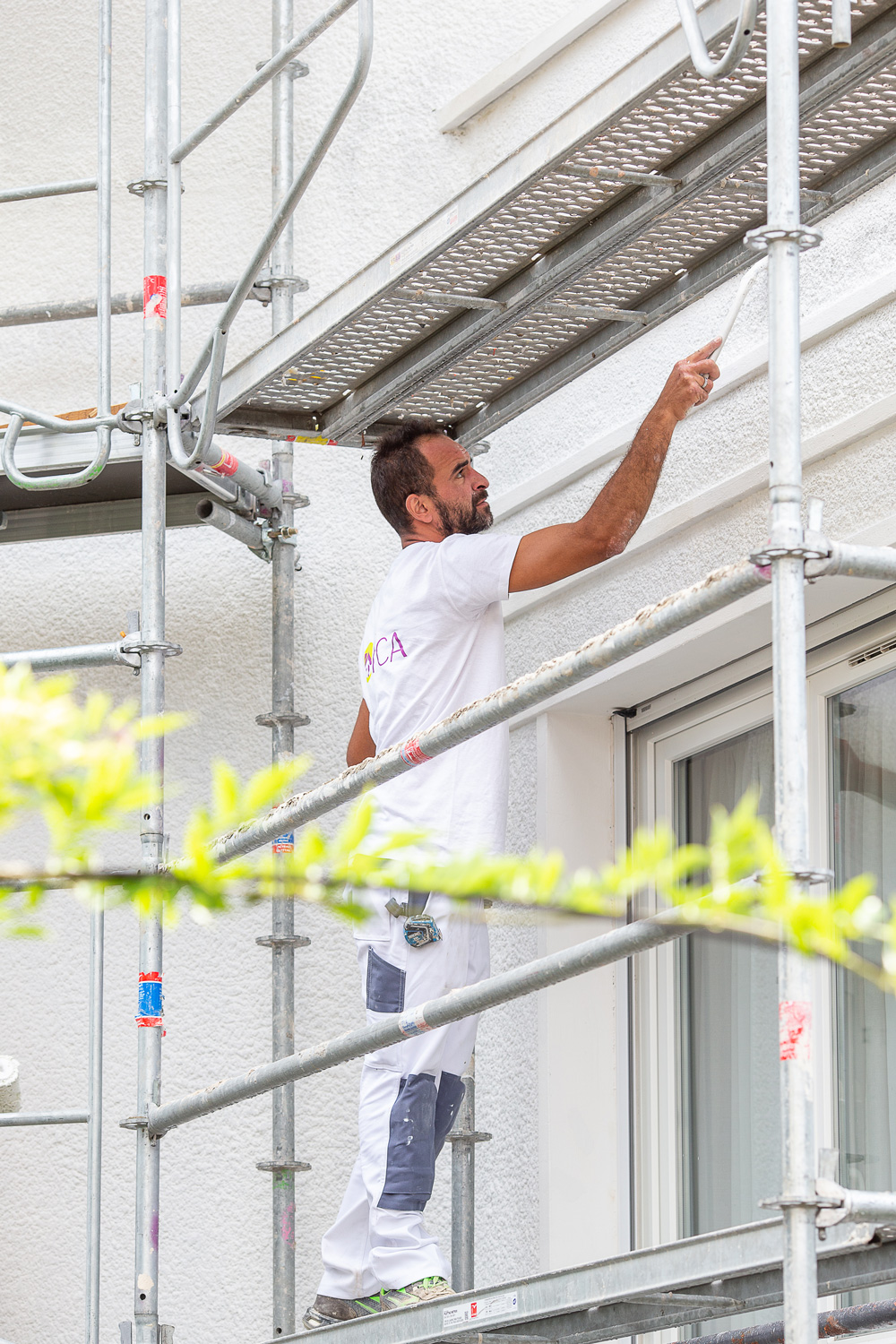 peinture-facade-2 Un homme sur un échafaudage en train de peindre une façade avec minutie et expertise.